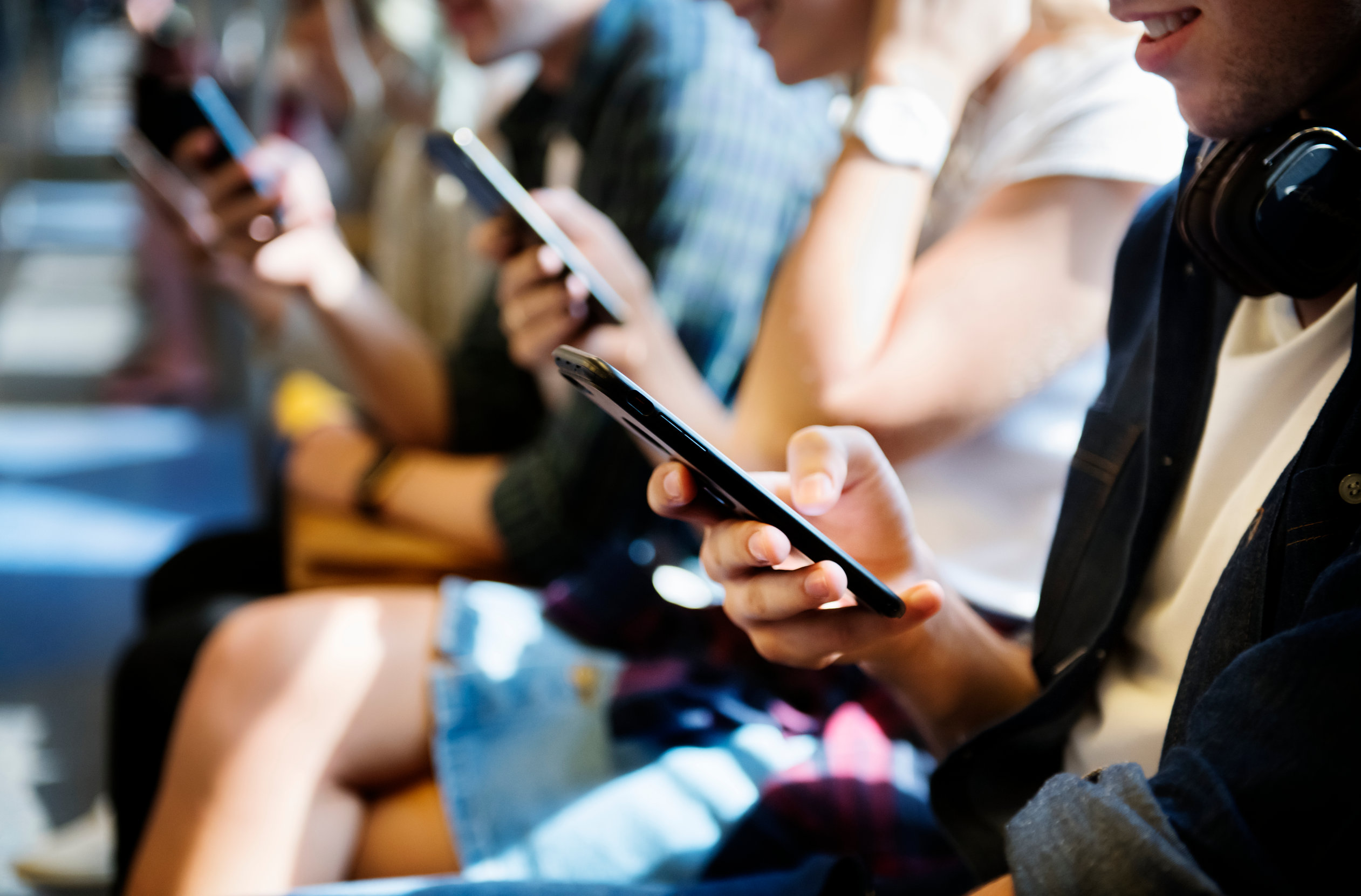 Group of young adult friends using smartphones in the subway